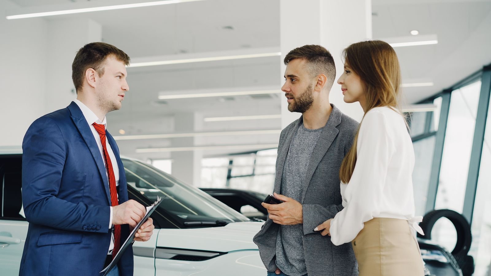 A salesperson with customers in a car showroom